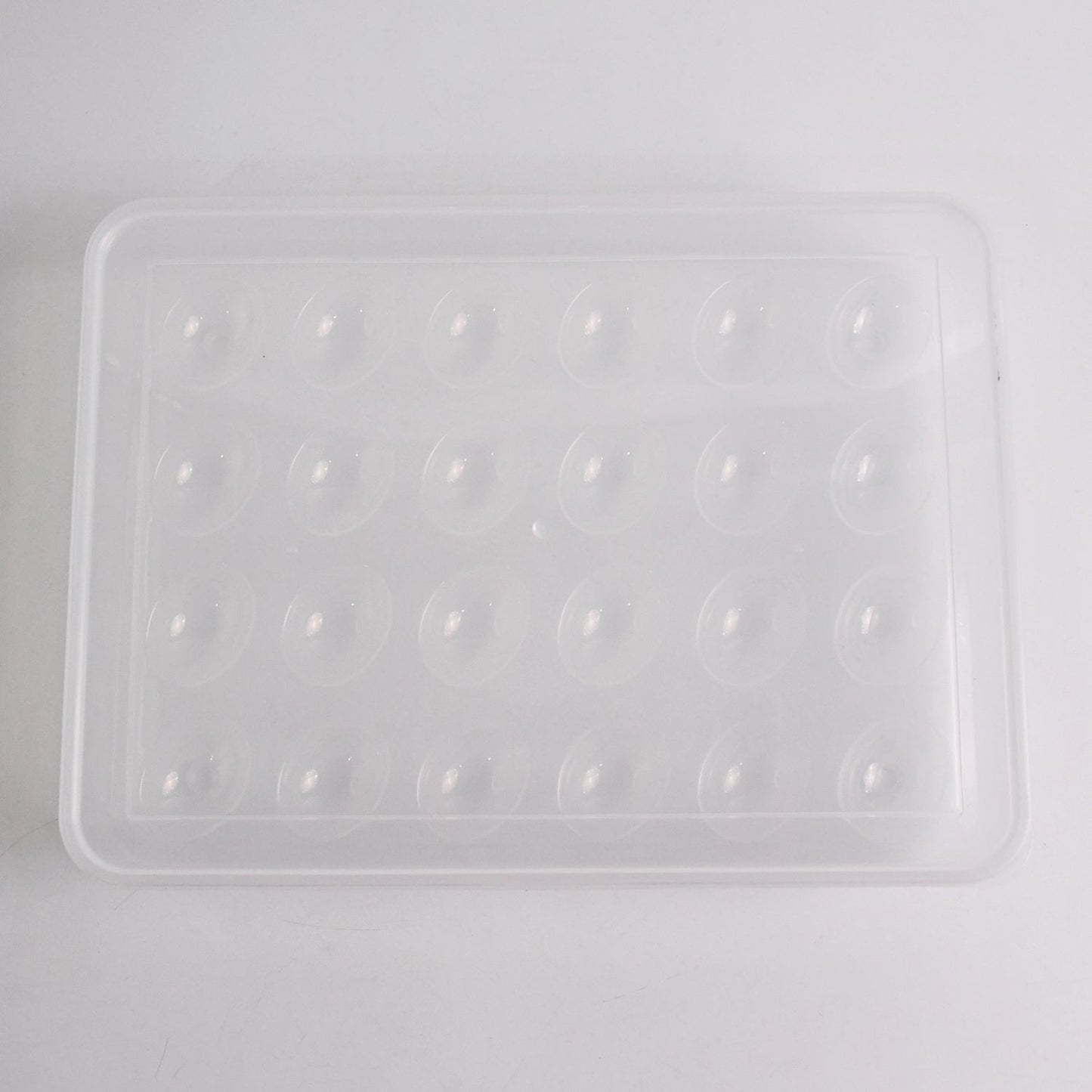 Clear plastic egg container next to traditional egg carton for size comparison