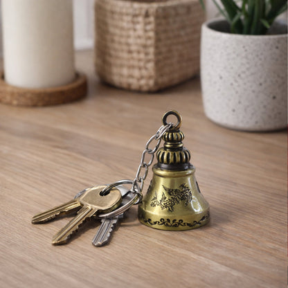 Close-up of the small ringing temple bell on the metal keychain, emphasizing detail.