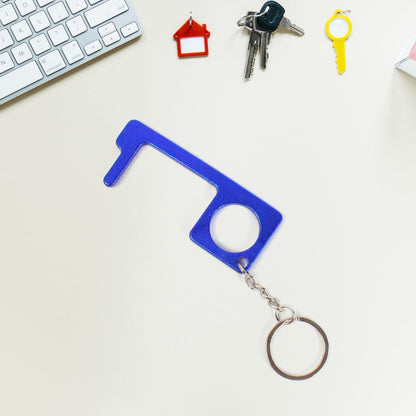 Hand holding Safe Touch Tool metal keychain used for hygienic door opening